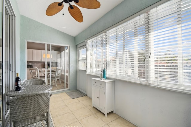 interior space featuring light tile patterned flooring, lofted ceiling, white cabinetry, ceiling fan, and backsplash