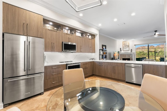 kitchen featuring sink, ornamental molding, appliances with stainless steel finishes, ceiling fan, and decorative backsplash