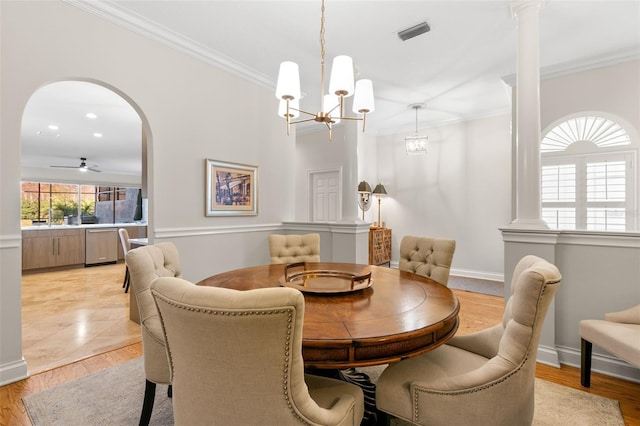 dining space featuring crown molding, ceiling fan with notable chandelier, decorative columns, and light hardwood / wood-style flooring