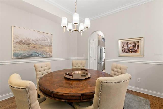 dining room with ornamental molding, hardwood / wood-style floors, and a notable chandelier