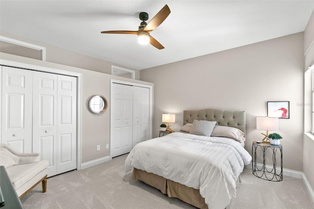 bedroom featuring two closets, light colored carpet, and ceiling fan