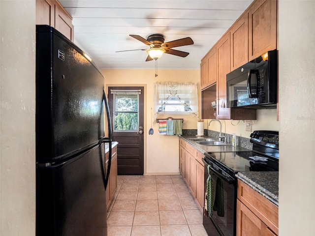 kitchen with sink, light tile patterned floors, ceiling fan, dark stone counters, and black appliances