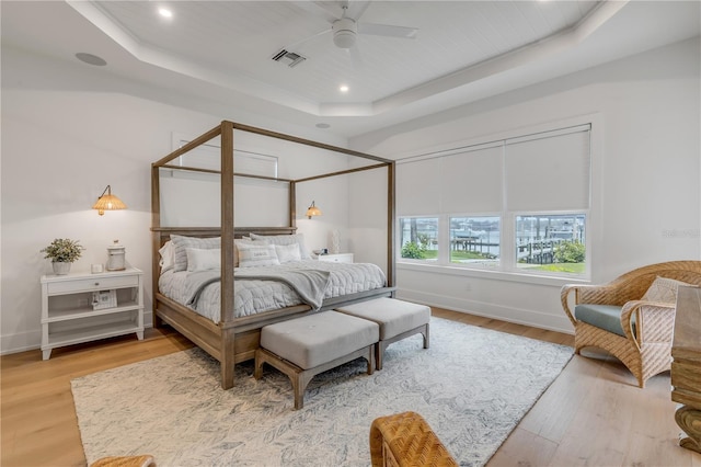 bedroom featuring hardwood / wood-style floors, ceiling fan, and a tray ceiling