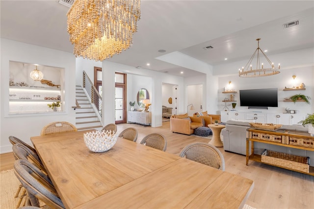 dining space with light wood-type flooring and an inviting chandelier