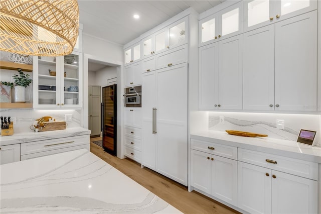 kitchen featuring tasteful backsplash, light stone countertops, oven, and white cabinets