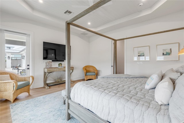 bedroom featuring light wood-type flooring and a tray ceiling