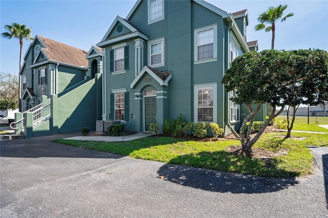 view of front facade with a front yard, cooling unit, and stucco siding