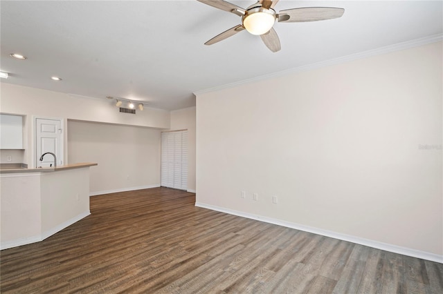 unfurnished living room featuring dark wood finished floors, a sink, baseboards, and ornamental molding