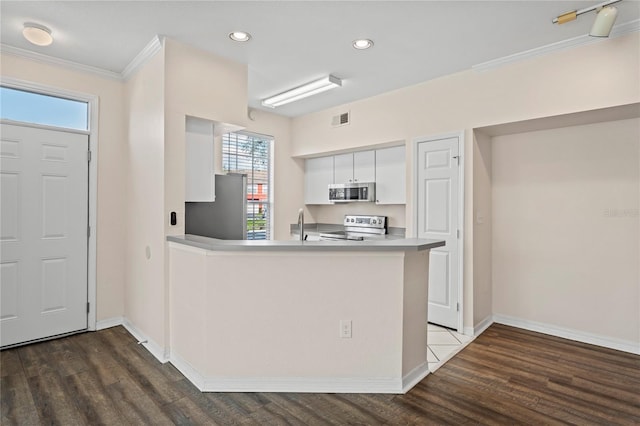 kitchen featuring visible vents, ornamental molding, dark wood finished floors, white cabinetry, and appliances with stainless steel finishes