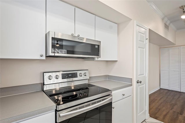 kitchen featuring visible vents, dark wood finished floors, ornamental molding, stainless steel appliances, and white cabinetry