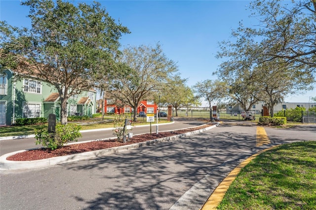 view of street with a gated entry, a residential view, curbs, and a gate