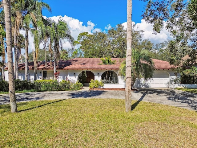 mediterranean / spanish-style house with a garage and a front lawn