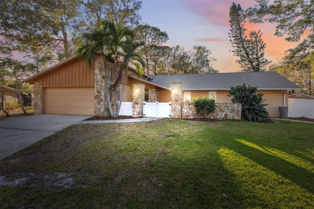 ranch-style home featuring a garage and a lawn