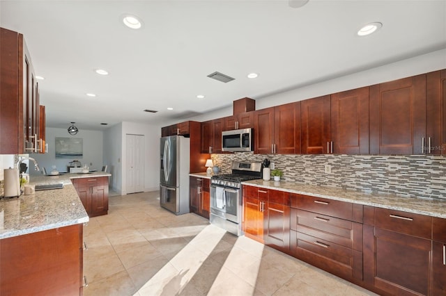 kitchen featuring sink, stainless steel appliances, light stone counters, tasteful backsplash, and kitchen peninsula