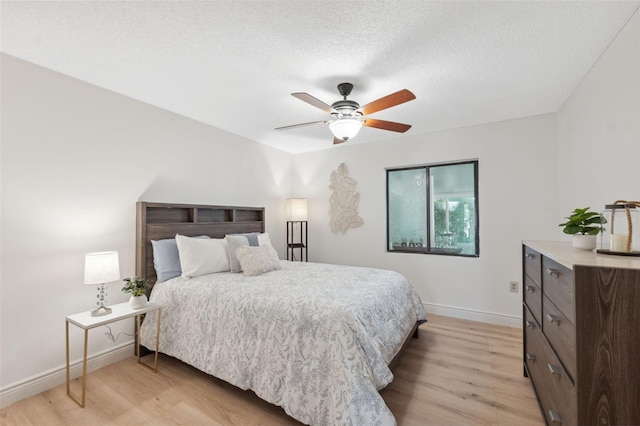 bedroom featuring ceiling fan, light hardwood / wood-style floors, and a textured ceiling