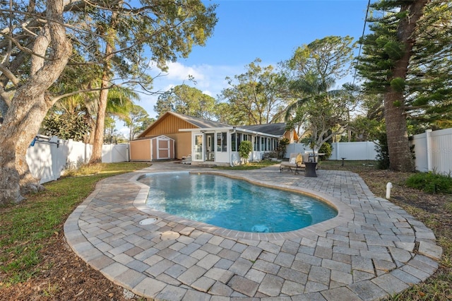 view of swimming pool with a storage shed, a patio area, and a sunroom