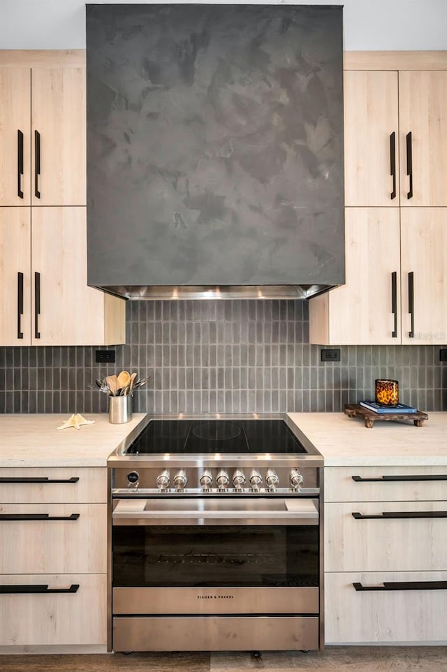 kitchen with stainless steel electric range, decorative backsplash, and light brown cabinets