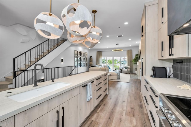 kitchen featuring pendant lighting, sink, a chandelier, range, and light wood-type flooring