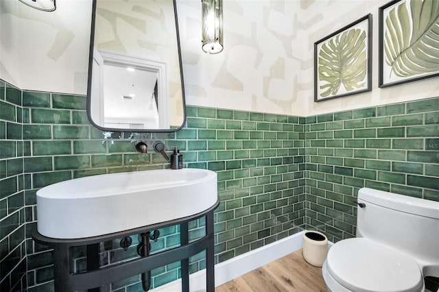 bathroom featuring sink, hardwood / wood-style floors, tile walls, and toilet