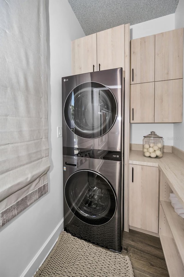 washroom with stacked washer and dryer, dark wood-type flooring, cabinets, and a textured ceiling