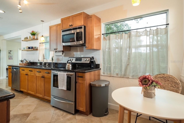 kitchen with pendant lighting, appliances with stainless steel finishes, sink, and decorative backsplash