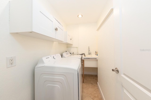 clothes washing area with sink, cabinets, washing machine and clothes dryer, and light tile patterned flooring