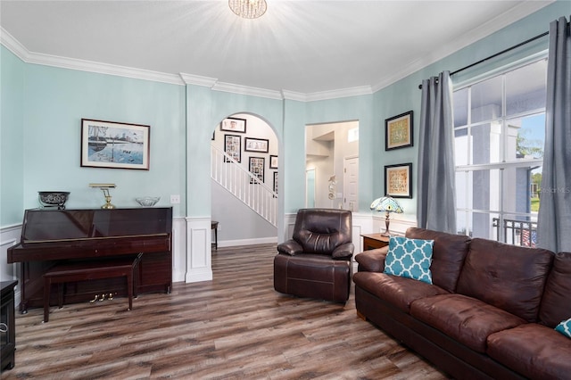 living area with crown molding, stairs, arched walkways, and wood finished floors