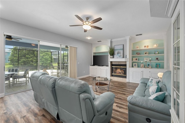 living area with ceiling fan, visible vents, built in shelves, wood finished floors, and baseboards