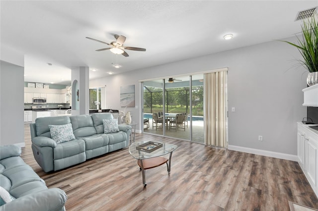 living room featuring baseboards, ceiling fan, visible vents, and wood finished floors