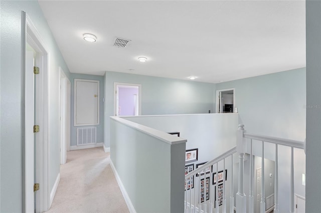 corridor featuring baseboards, visible vents, light carpet, and an upstairs landing