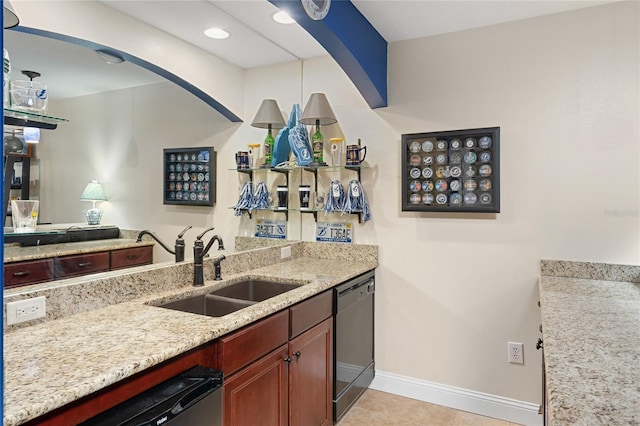 kitchen with a sink, baseboards, light stone countertops, and dishwasher