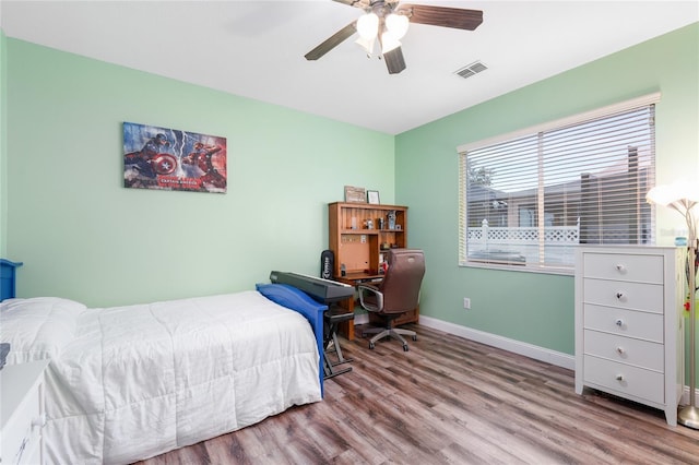 bedroom featuring baseboards, a ceiling fan, wood finished floors, and visible vents