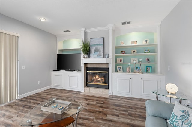 living room featuring baseboards, visible vents, wood finished floors, and a tile fireplace