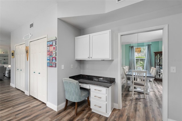 office area with baseboards, visible vents, dark wood-style floors, and built in desk