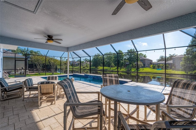 outdoor pool featuring a ceiling fan, a lanai, a water view, and a patio area