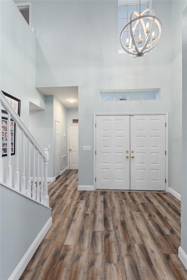 entryway featuring an inviting chandelier, baseboards, a high ceiling, and wood finished floors
