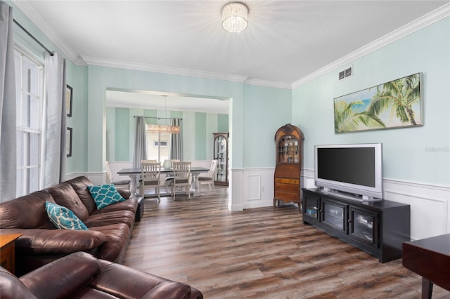 living area with an inviting chandelier, ornamental molding, wood finished floors, and visible vents