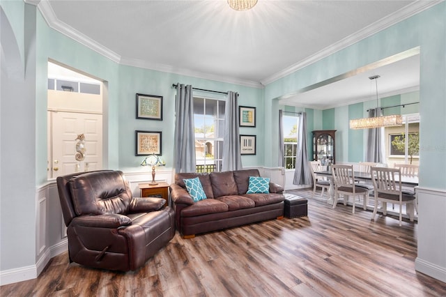 living room with crown molding, wood finished floors, and a wainscoted wall
