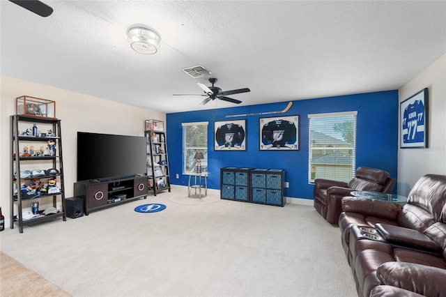 carpeted living room with visible vents, a ceiling fan, baseboards, and a textured ceiling