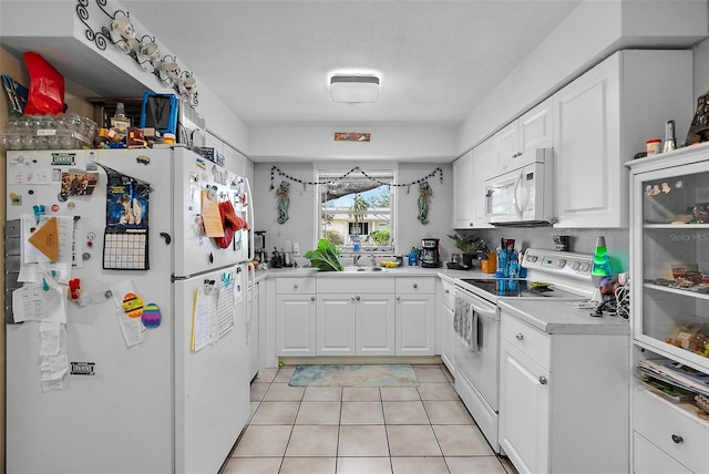 kitchen with light countertops, white cabinetry, light tile patterned floors, and white appliances