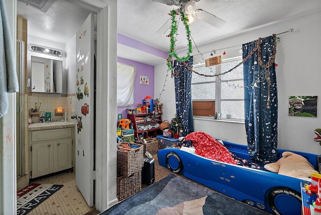 bedroom featuring a sink, light floors, connected bathroom, and visible vents