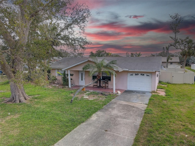 view of front of property featuring a lawn, concrete driveway, an attached garage, and fence