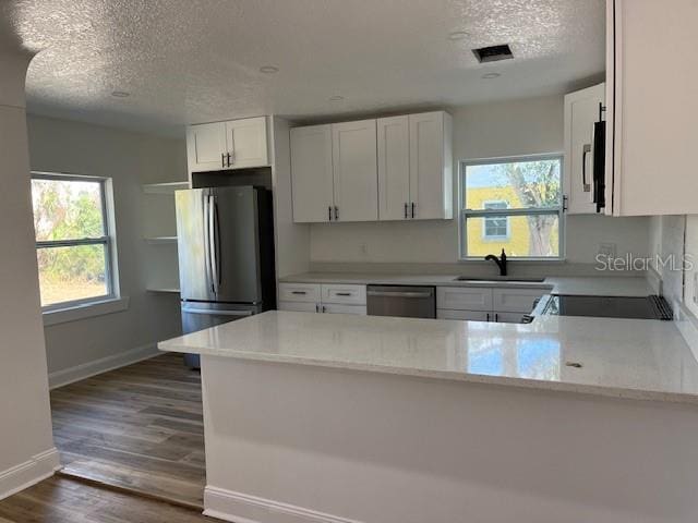 kitchen featuring white cabinetry, appliances with stainless steel finishes, sink, and kitchen peninsula