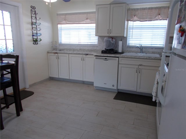 kitchen with a healthy amount of sunlight, sink, white appliances, and white cabinets