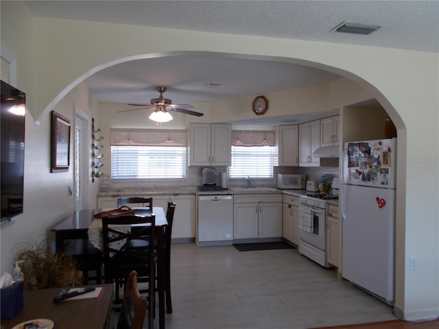 kitchen with tasteful backsplash, white appliances, sink, and white cabinets