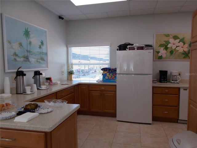 kitchen featuring white appliances, a paneled ceiling, and light tile patterned flooring