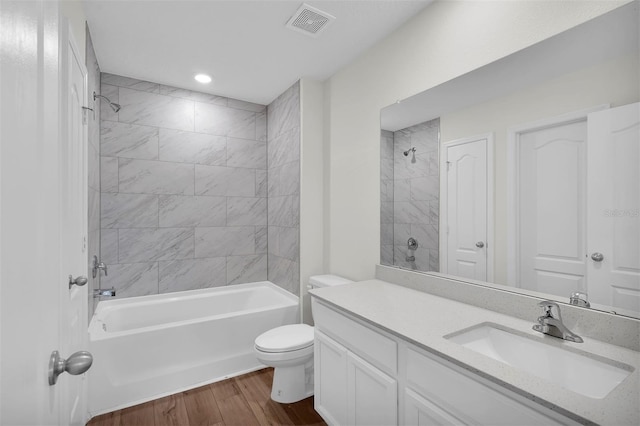 full bathroom featuring vanity, tiled shower / bath combo, toilet, and hardwood / wood-style flooring