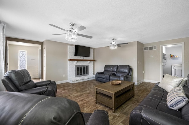 living room with dark hardwood / wood-style floors, a textured ceiling, and a fireplace