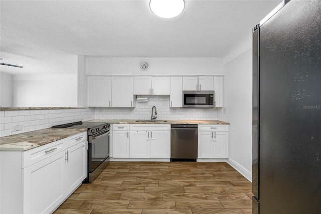 kitchen with appliances with stainless steel finishes, sink, white cabinets, and backsplash