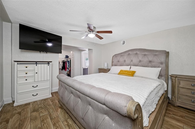 bedroom featuring a walk in closet, hardwood / wood-style floors, a textured ceiling, and a closet